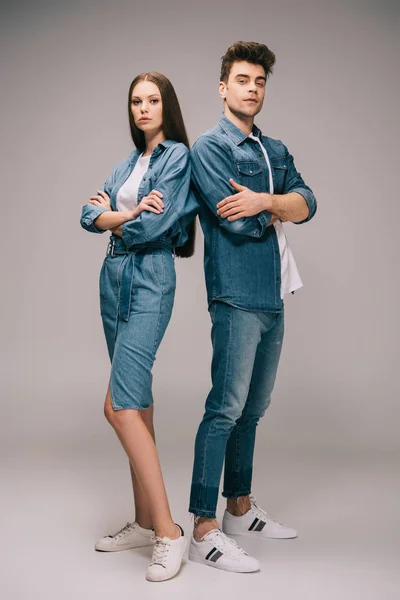 Novia en vestido de mezclilla y novio en jeans y camisa con brazos cruzados mirando a la cámara — Stock Photo