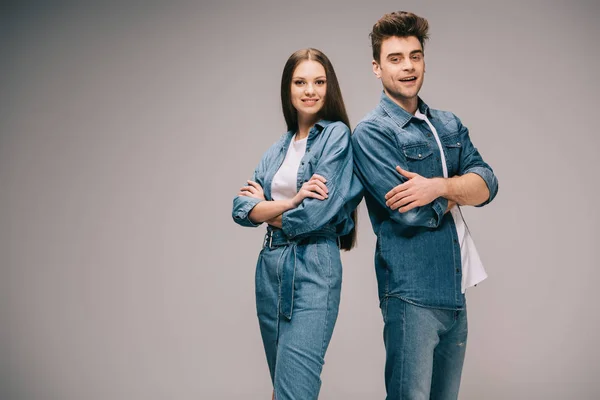 Novia sonriente en vestido de mezclilla y novio en jeans y camisa con los brazos cruzados mirando a la cámara - foto de stock