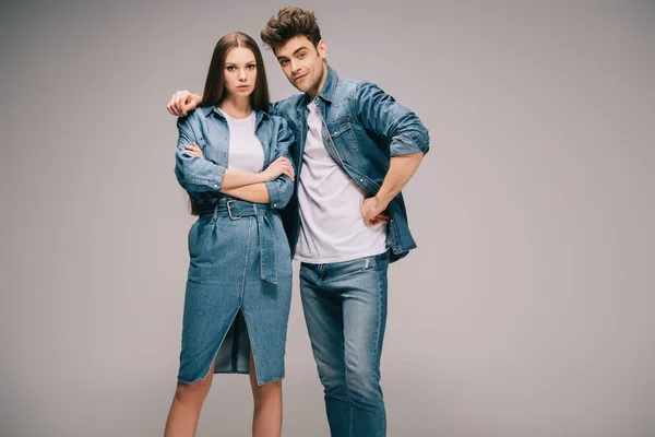 Atractiva novia en vestido de mezclilla y novio en jeans y camisa abrazando y mirando a la cámara - foto de stock