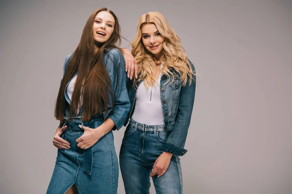 Happy blonde and brunette women in denim clothes smiling and looking at camera — Stock Photo