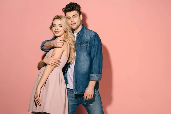 Smiling girlfriend and handsome boyfriend in denim shirt hugging and looking at camera — Stock Photo