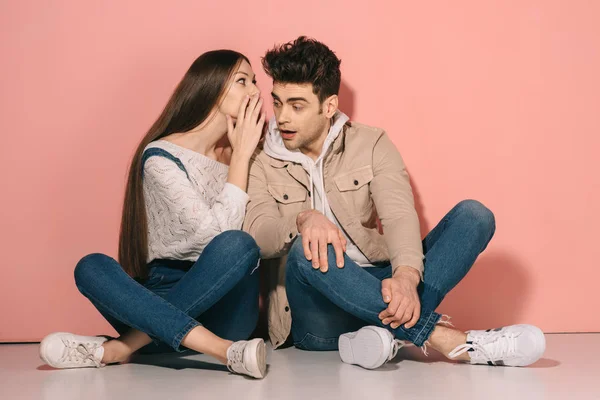 Brunette and beautiful girlfriend in denim overalls and handsome boyfriend sitting on floor and talking — Stock Photo