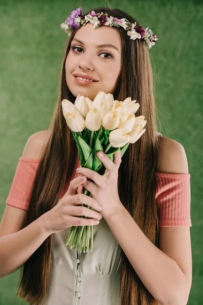 Lächelnde schöne und brünette Frau im Kranz mit Tulpen und Blick in die Kamera — Stockfoto