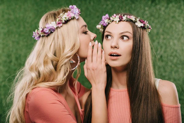 Shocked brunette and beautiful blonde women in wreaths talking and looking away — Stock Photo