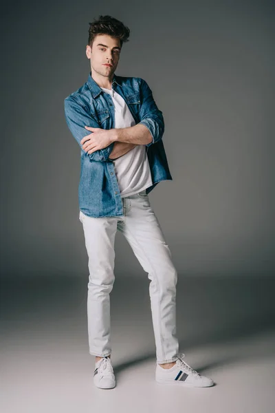 Homem bonito em camisa jeans e jeans com braços cruzados olhando para a câmera — Fotografia de Stock