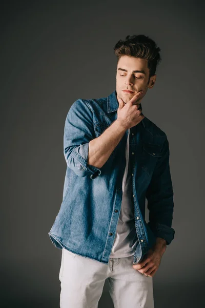 Bel homme en denim chemise et jeans regardant loin sur fond gris — Photo de stock