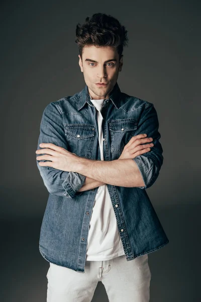 Handsome and brunette man with crossed arms looking at camera isolated on black — Stock Photo