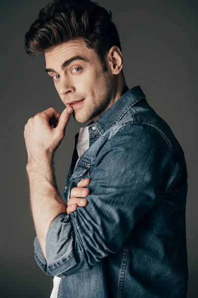 Handsome and brunette man in denim shirt looking at camera isolated on black — Stock Photo