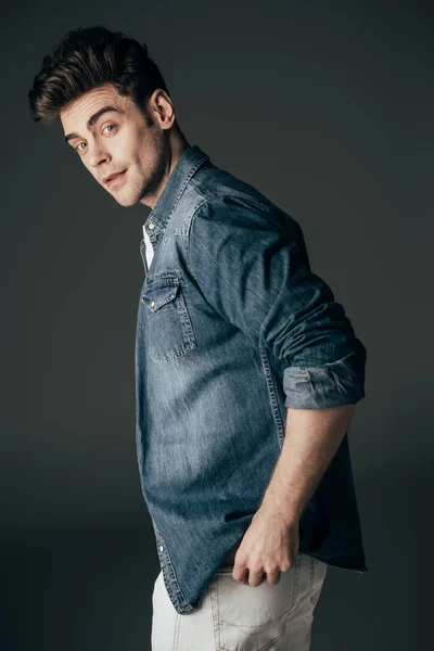 Handsome and brunette man in denim shirt looking at camera isolated on black — Stock Photo