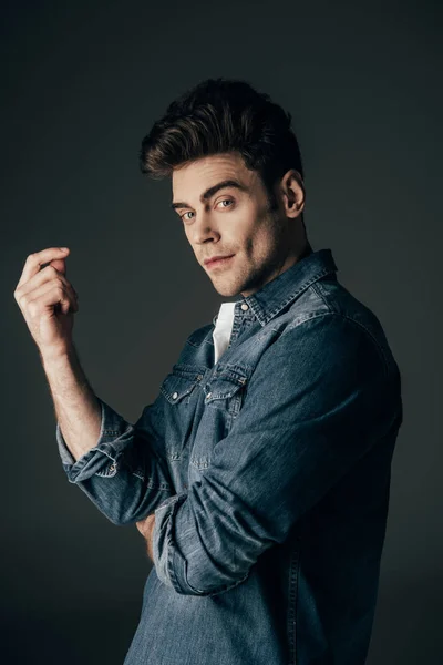 Bonito e morena homem no denim camisa olhando para câmera isolada no preto — Fotografia de Stock