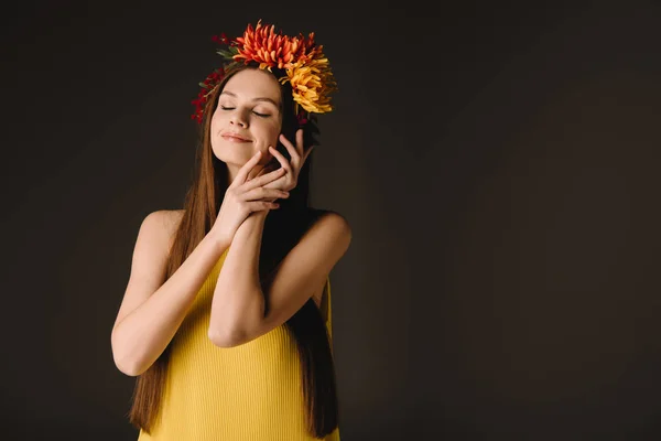 Beautiful and brunette woman with closed eyes in wreath isolated on black — Stock Photo