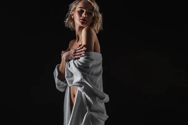 Красива сексуальна молода жінка в білому халаті позує ізольовано на чорному з копіювальним простором — стокове фото