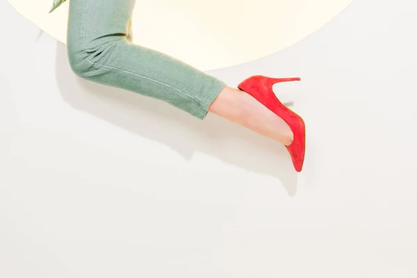 Обрезанный вид молодой женщины в стильных брюках и красных высоких каблуках на белом с копировальным пространством — стоковое фото