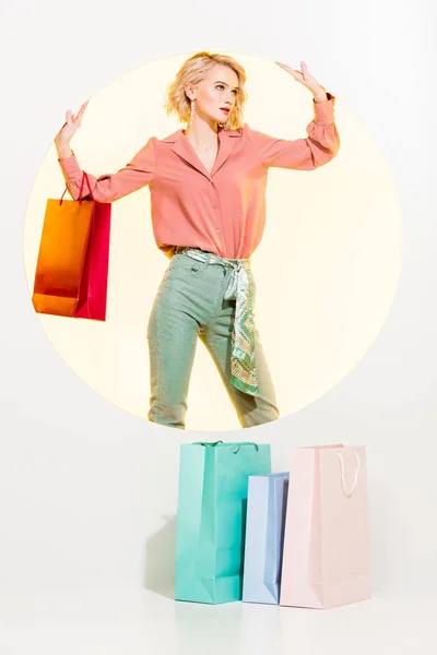 Bela menina elegante com sacos de compras posando no branco com círculo amarelo — Fotografia de Stock