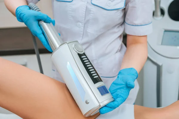 Vista recortada del cosmetólogo haciendo endosferas terapia para la pierna - foto de stock