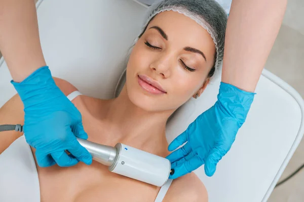 Partial view of cosmetologist in rubber gloves doing  therapy for chest - foto de stock