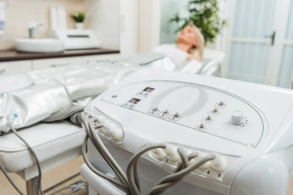 Chica en el sofá de belleza y el aparato de presoterapia en la clínica - foto de stock