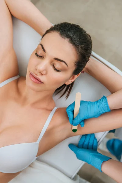 Vista ritagliata di cosmetologo utilizzando coltello stucco per depilazione cera ascella — Foto stock