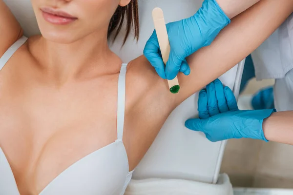 Cropped view of cosmetologist using putty knife for armpit wax depilation — Stock Photo