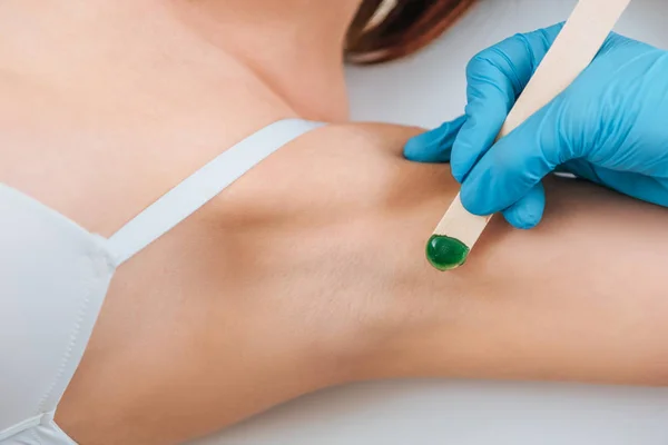 Cropped view of cosmetologist using putty knife for armpit wax depilation — Stock Photo