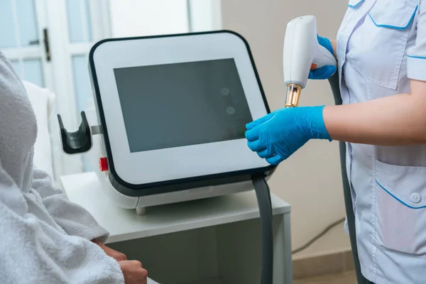 Vista ritagliata di cosmetologo con dispositivo laser in clinica — Foto stock