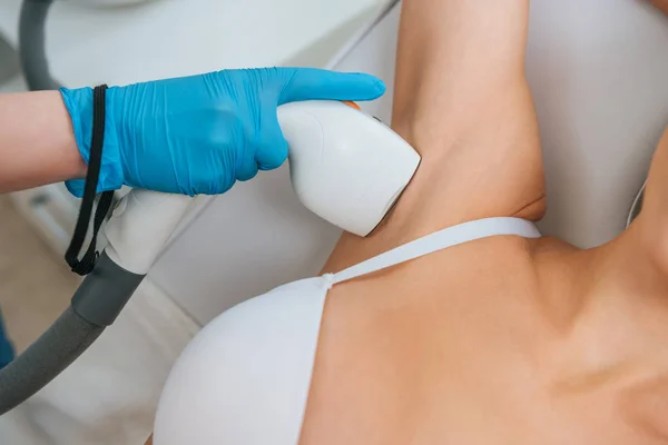 Cropped view of cosmetologist doing laser hair removal procedure on armpit — Stock Photo