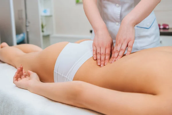Vista parcial de masajista haciendo masaje de espalda a chica en mesa de masaje — Stock Photo