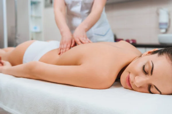 Partial view of masseur doing back massage to girl on massage table — Stock Photo