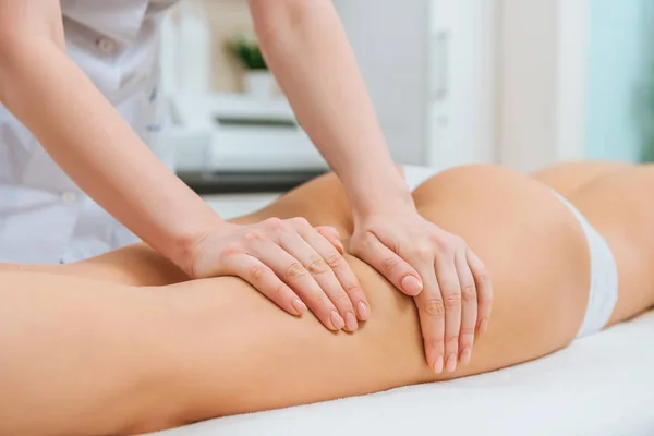 Vista parziale del massaggiatore che fa massaggio alle gambe alla donna — Foto stock