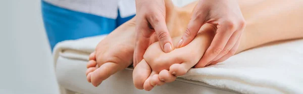 Vue panoramique de masseur faisant massage des pieds à la femme sur la table de massage — Photo de stock