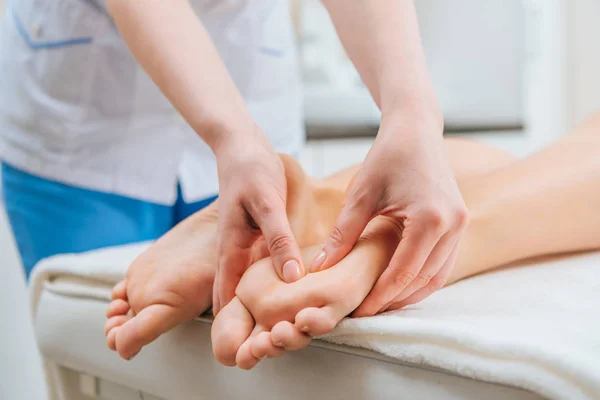 Обрізаний вид масажиста робить масаж ніг жінці на масажному столі — стокове фото
