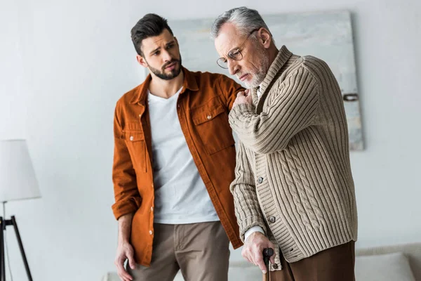 Handsome bearded son looking at upset senior father in glasses — Stock Photo