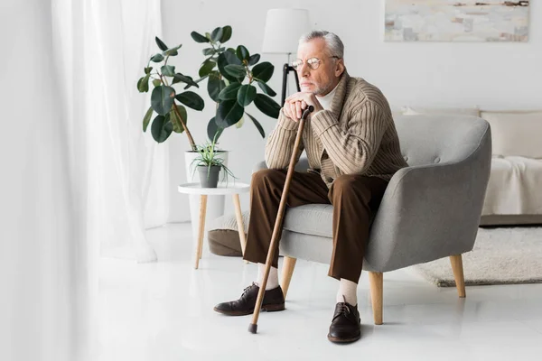 Pensivo aposentado homem em óculos sentado em poltrona em casa — Fotografia de Stock