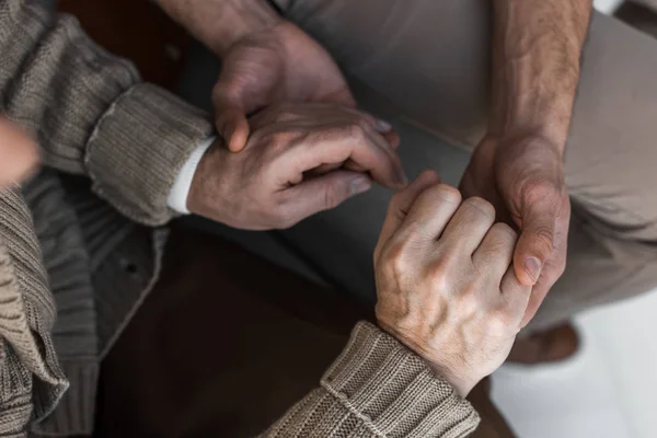 Cropped view of retired father and son holding hands — Stock Photo