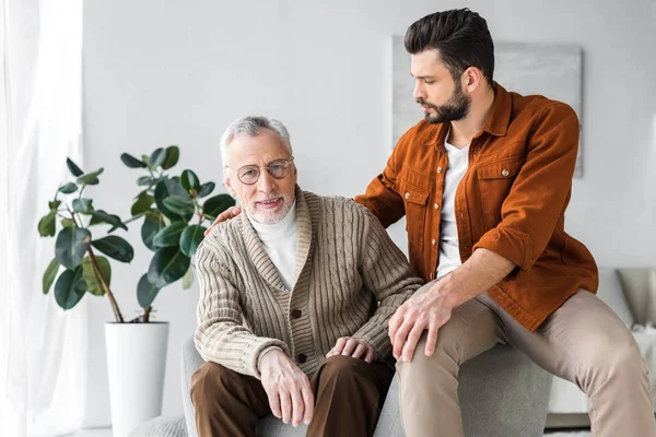 Glücklicher Senior-Vater mit Brille sitzt neben hübschem Sohn zu Hause — Stockfoto