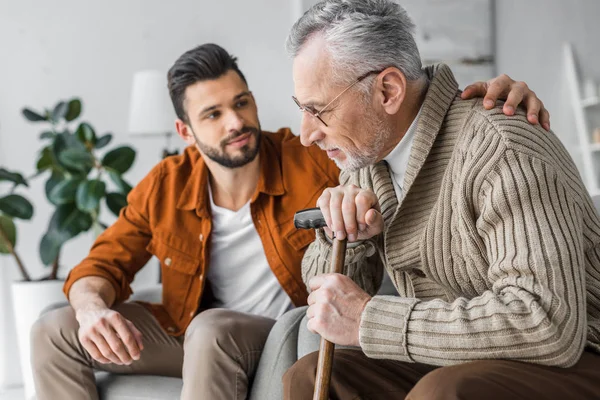 Foyer sélectif de l'homme âgé et beau fils assis à la maison — Photo de stock