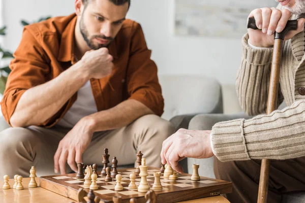 Ausgeschnittener Blick auf Vater und Sohn im Ruhestand, die zu Hause Schach spielen — Stockfoto