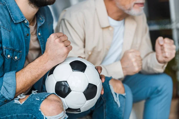 Recortado vista de hombre mayor viendo campeonato con hijo celebración de fútbol - foto de stock