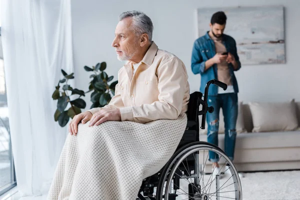 Focalizzazione selettiva dell'uomo anziano disabile sulla sedia a rotelle vicino al figlio — Foto stock