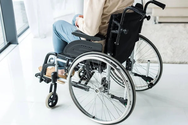 Vista recortada del hombre jubilado discapacitado sentado en silla de ruedas en casa - foto de stock