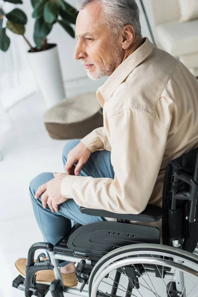 Hombre jubilado discapacitado sentado en silla de ruedas en casa - foto de stock