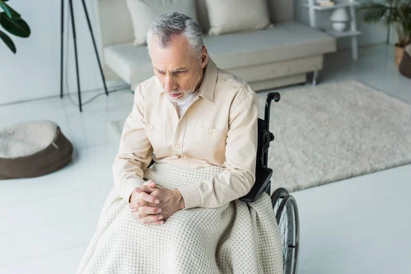 Vista aérea del triste hombre jubilado discapacitado sentado en silla de ruedas con las manos apretadas - foto de stock