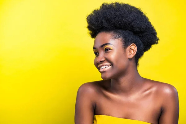 Freudig lächelnde afrikanisch-amerikanische Mädchen mit Make-up isoliert auf gelb — Stockfoto