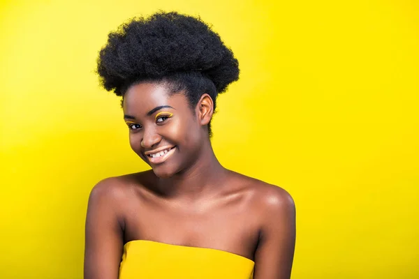 Alegre sonriente chica afroamericana con maquillaje aislado en amarillo - foto de stock