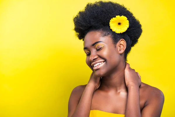 Alegre sonriente mujer afroamericana con flor en amarillo - foto de stock