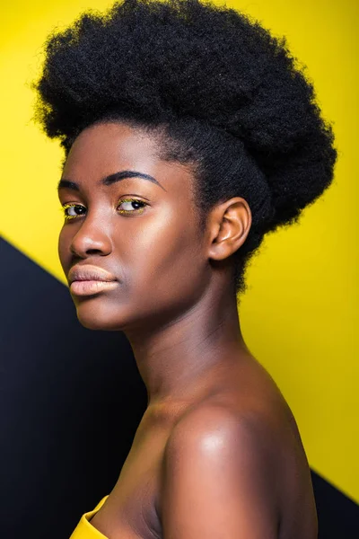 Attractive african american girl looking at camera on black and yellow — Stock Photo