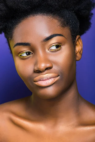 Belle jeune femme afro-américaine avec des cils jaunes sur violet — Photo de stock