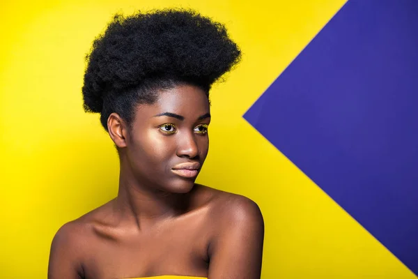 Mujer afroamericana soñadora mirando hacia otro lado en amarillo y púrpura - foto de stock