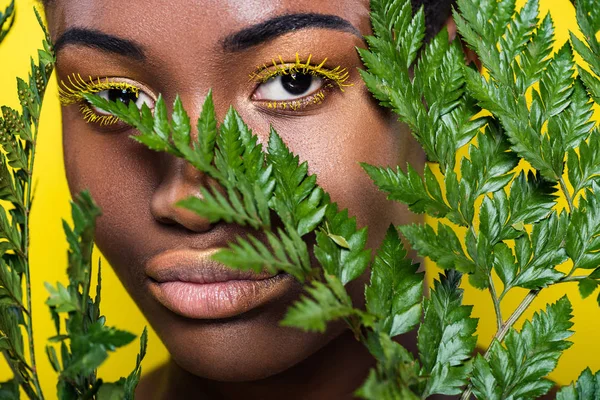 Красива афроамериканець дівчина з зеленим папороті ізольовані на жовтий — стокове фото