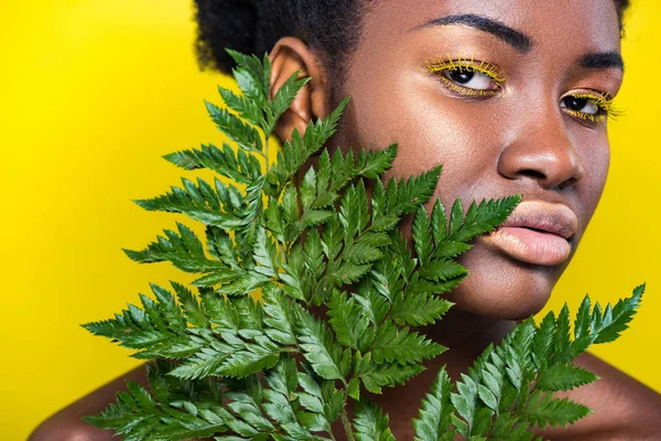 Bella ragazza afro-americana con felce verde isolata sul giallo — Foto stock